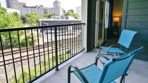Ein Balkon mit zwei Stühlen und Blick auf Gleise sowie Gebäude im Hintergrund.