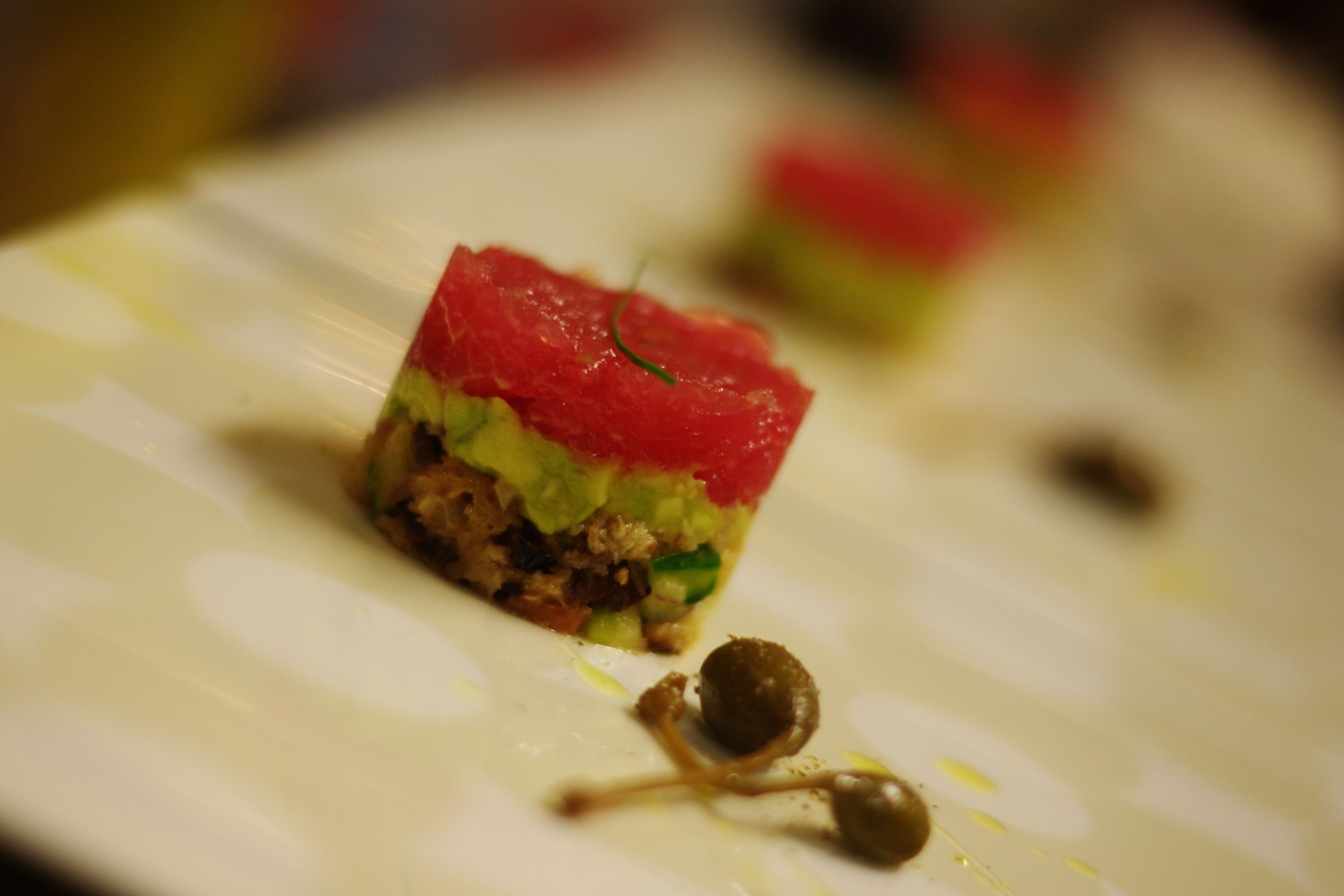 A close-up of a dish with red topping and green vegetables on a plate.
