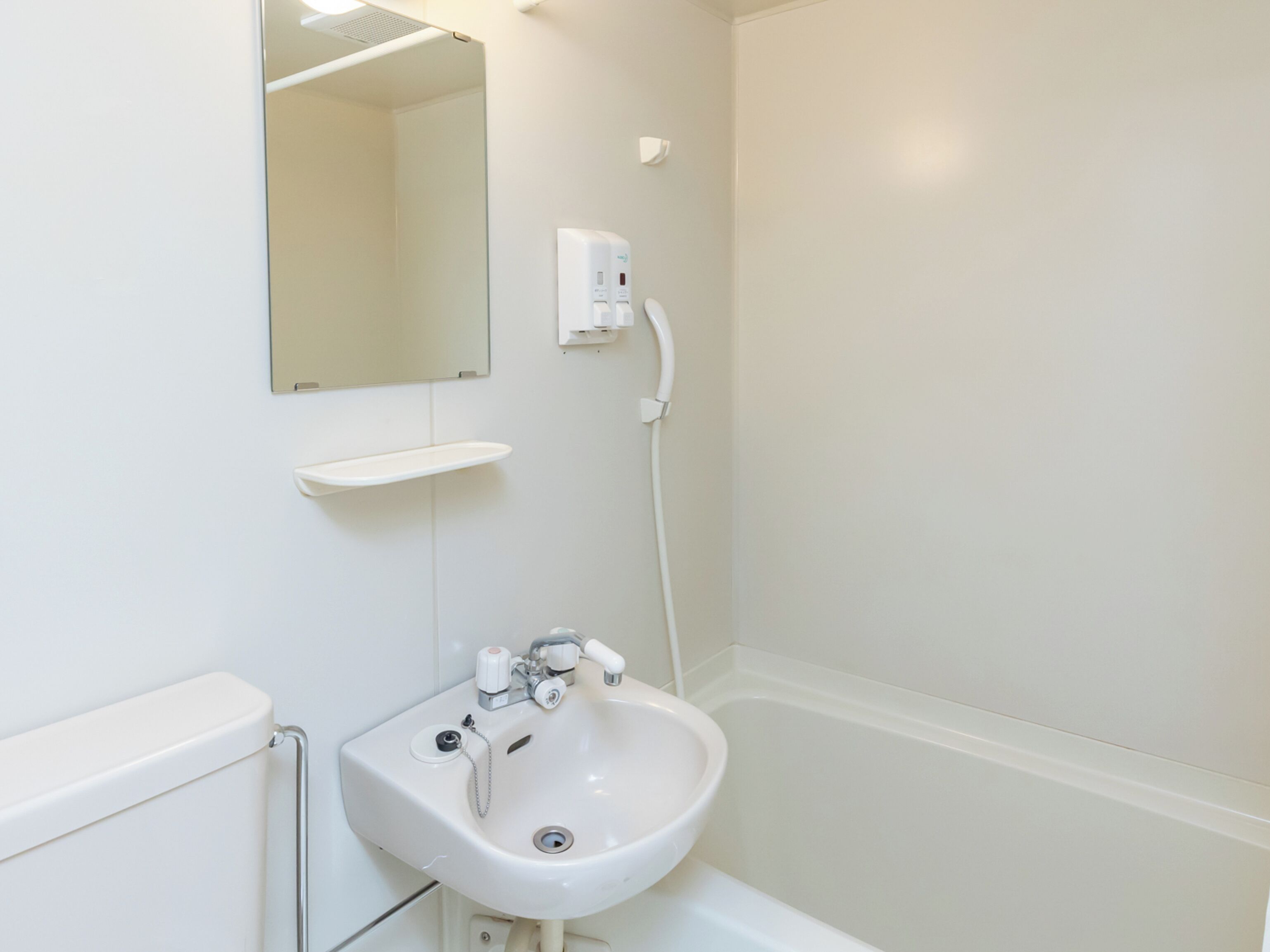 A bathroom with a sink, mirror, and a hand dryer.