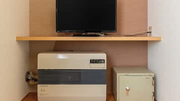 Una habitación con una televisión en un estante de madera, un aire acondicionado blanco y una caja fuerte pequeña y blanca.