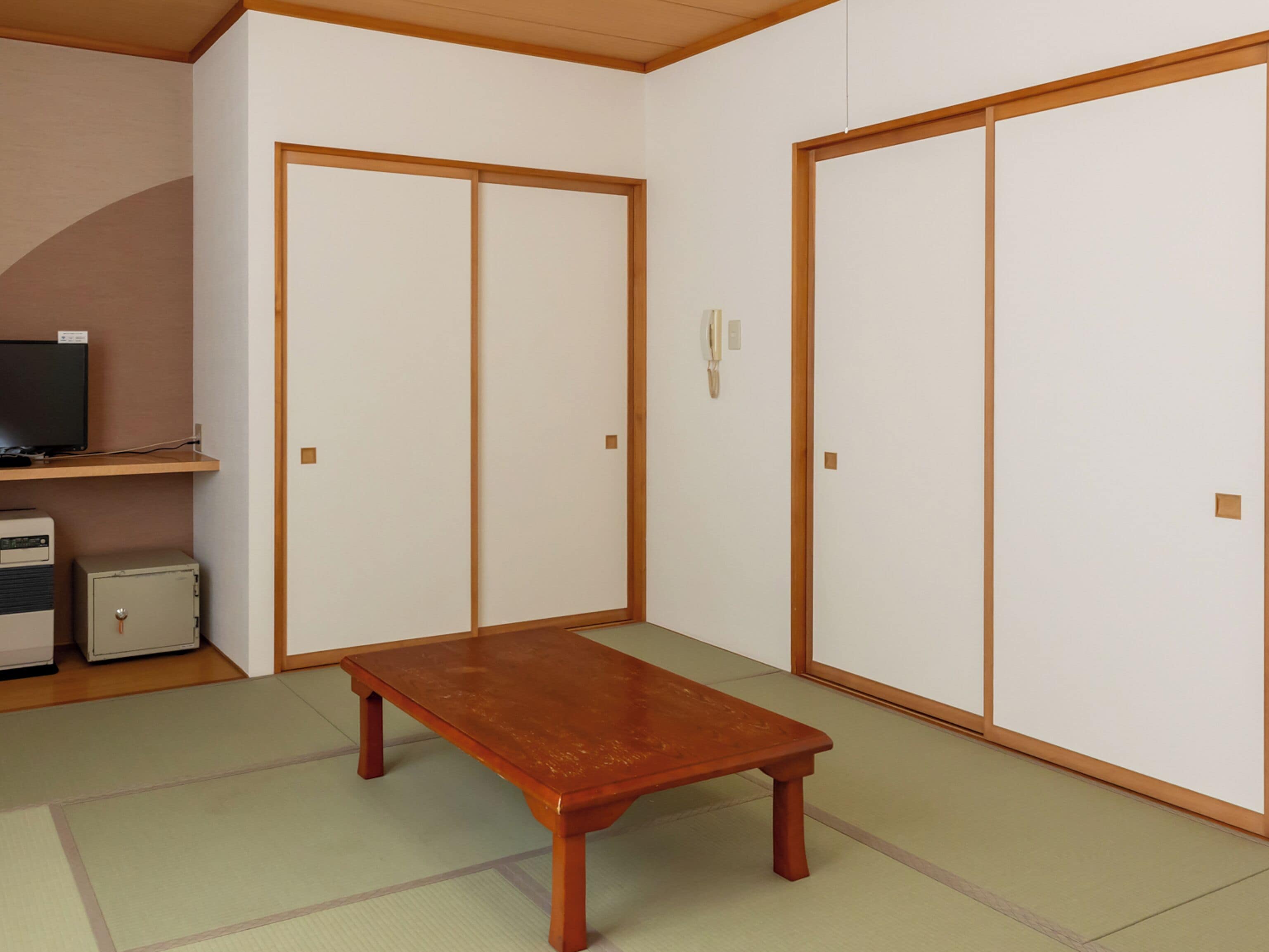 A room with a wooden table, a television, and a cabinet.