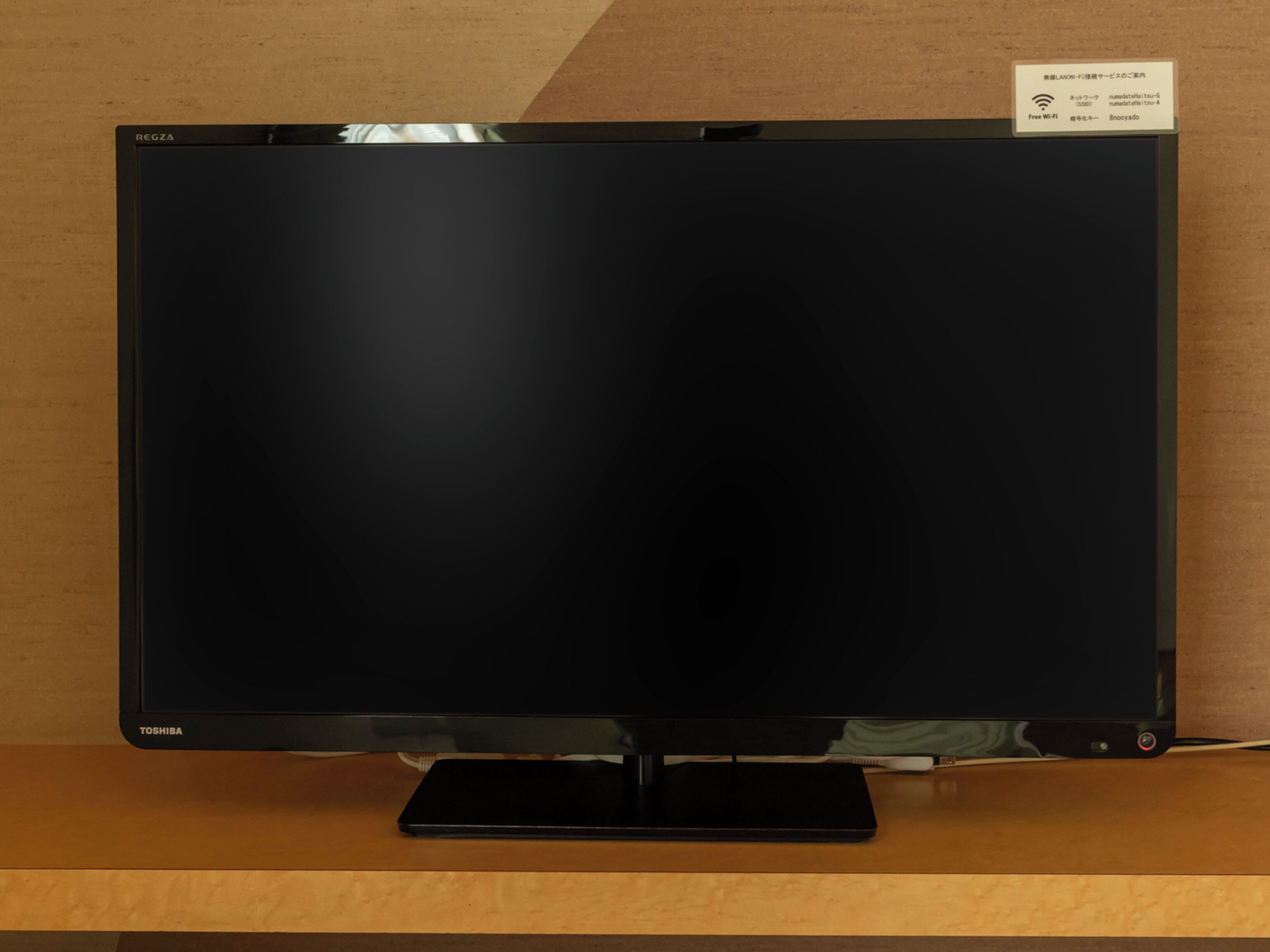 A flat-screen TV on a wooden stand with a sign indicating Free Wi-Fi availability.