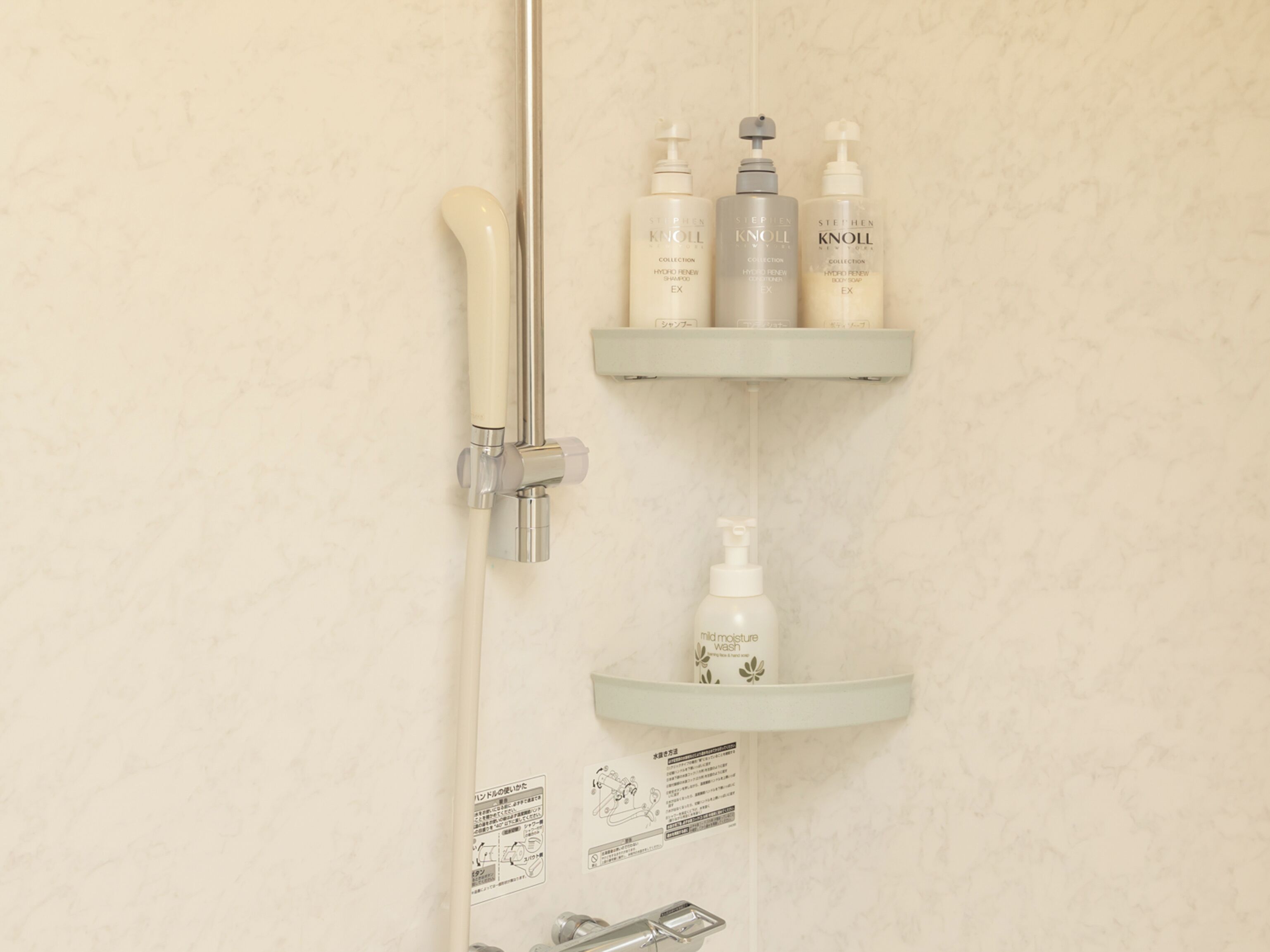 A shower area with a handheld showerhead, a wall-mounted faucet, and shelves holding toiletries.