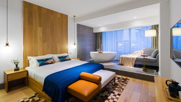 A modern hotel room with a large bed, a bathtub, a sofa, and a view of the city. - Hexi Boutique Hotel Chengdu (Chengdu)