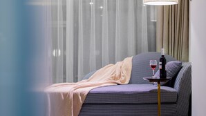 A modern living room with a sofa, a table with a bottle and glass, and sheer curtains. - Hexi Boutique Hotel Chengdu (Chengdu)
