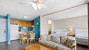 A compact hotel room with a kitchenette, a sofa, a bed, and a dining area. - Royal Kuhio 1602 - Spacious one‑bedroom condominium w/ Stunning Mountain Views in the Heart of Waikiki! (Waikiki)