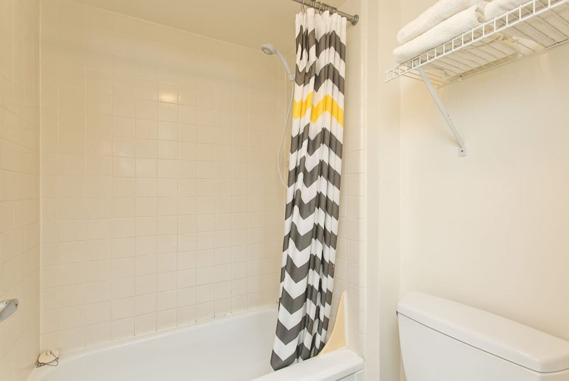 Une salle de bain avec un rideau de douche, une baignoire blanche et un porte-serviettes avec des serviettes.