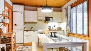 A compact kitchen with white cabinets, a microwave, a stove, and a dining table with benches. - Rome 10 by Interhome (Pudasjärvi)
