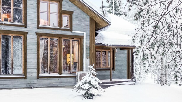 A two-story wooden house with large windows and a covered porch, surrounded by snow-covered trees. - Rome 10 by Interhome (Pudasjärvi)
