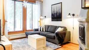 A cozy living room with a grey sectional sofa, a wooden coffee table, and a fireplace. - Rome 10 by Interhome (Pudasjärvi)
