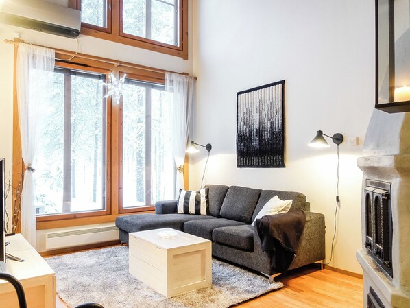 A living room with a grey sofa, a white coffee table, and a fireplace. - Rome 10 by Interhome (Pudasjärvi)