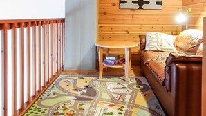 A cozy cabin interior with a wooden floor, a small round table with books, a leather sofa, and a wall-mounted light fixture. - Rome 10 by Interhome (Pudasjärvi)