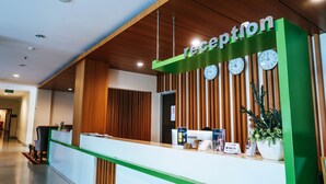 Zona de recepción con mostrador, un reloj y un cartel que indica que la recepción está abierta.