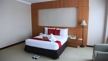 Une chambre d’hôtel avec un grand lit, une tête de lit en bois, des tables de chevet, une lampe et une chaise.