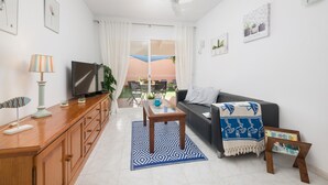 Un salon moderne avec un canapé, un téléviseur, un meuble en bois et un tapis à motifs.