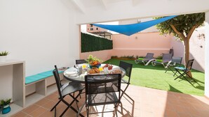 Une terrasse extérieure avec une table ronde, des chaises et un auvent bleu.