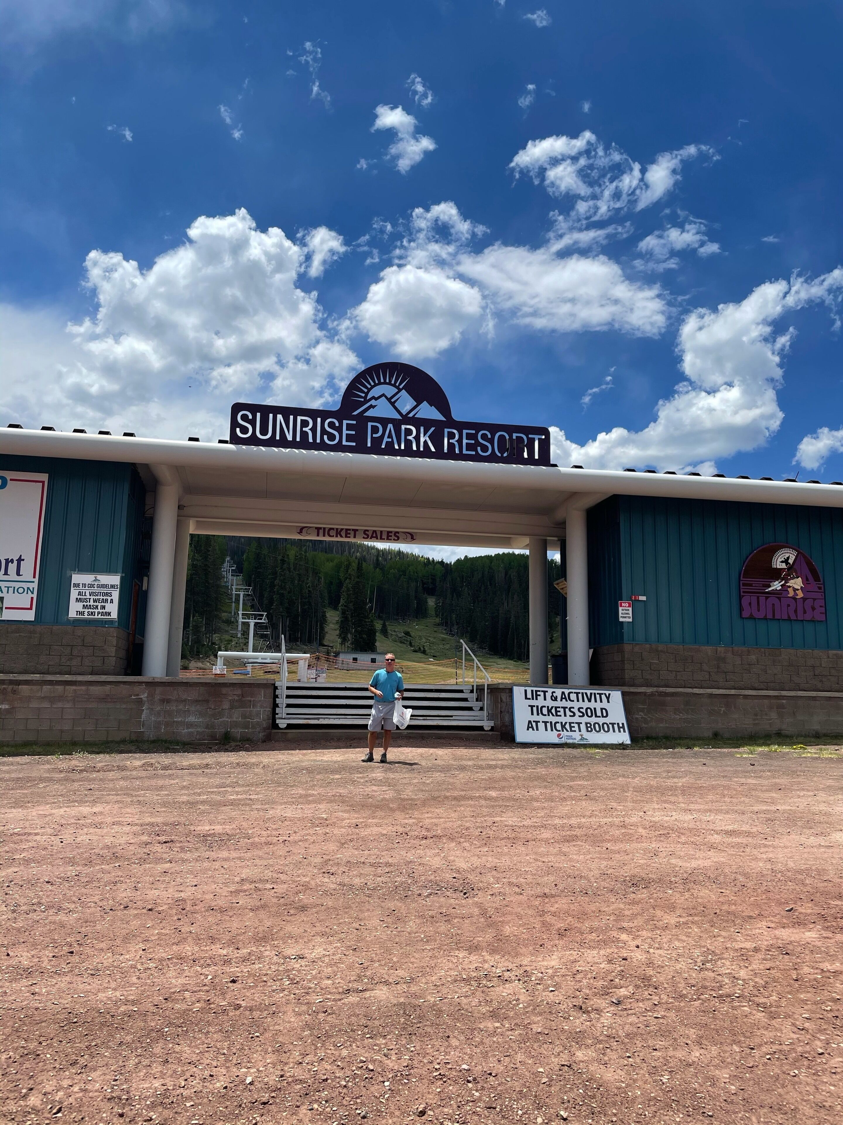 Une enseigne indiquant le Sunrise Park Resort, avec un ciel dégagé et une personne debout devant.