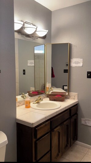 A bathroom with a large mirror, a sink, and a vanity with dark wooden cabinets. - Cozy & Comfortable Cabin in The Pinetop White Mountains - LONG TERM SPECIAL (Pinetop)