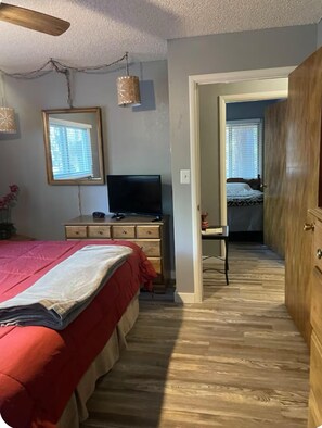 A bedroom with a bed, dresser, TV, and a hallway leading to another room. - Cozy & Comfortable Cabin in The Pinetop White Mountains - LONG TERM SPECIAL (Pinetop)