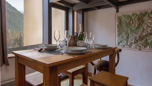 A wooden dining table set with plates, glasses, and a bottle, with a mountain view through a window. - Grand Roc C314 280m from Slopes, View, Parking & WiFi, Argentière (Chamonix), France (Argentière (Chamonix))
