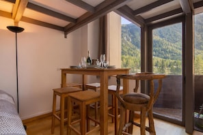 A dining area with a table set for four, wooden chairs, and a bottle of champagne. - Résidence Grand Roc - Campanules 314, Argentière (Chamonix), France (Argentière (Chamonix))