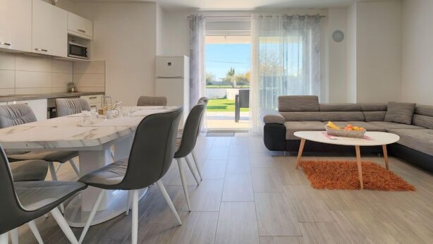 Una sala de estar moderna con comedor, un sofá y una pequeña mesa con fruta.