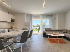 Un salon moderne comprenant un coin repas, un canapé et une petite table sur laquelle sont disposés des fruits.