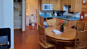 A wooden interior with a dining area, kitchen, and upper-level balcony. - Homesteader Cabin at Coliseum Mountain Resort (Nordegg)