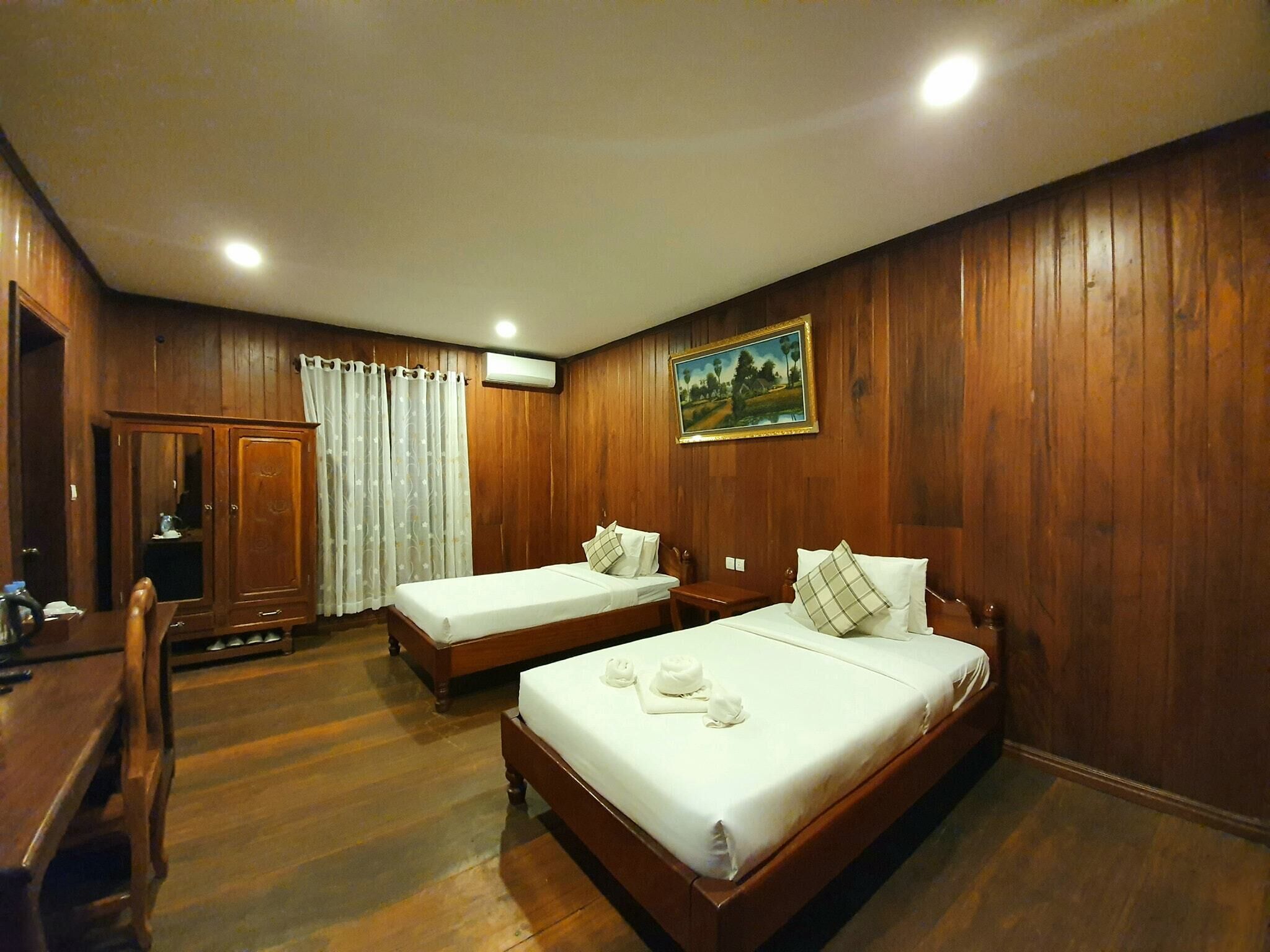 Une chambre avec deux lits en bois, un bureau et une armoire.