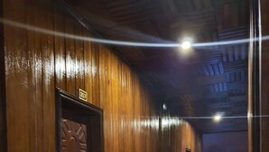 A hallway with wooden paneling and a patterned floor, leading to a door marked with the number 307. - Sam Moon's Hotel Angkor (Siem Reap)