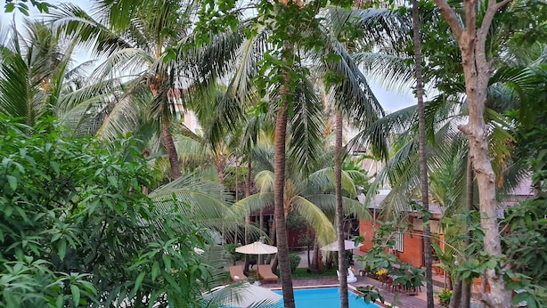 A pool surrounded by palm trees and a brick building. - Sam Moon's Hotel Angkor (Siem Reap)