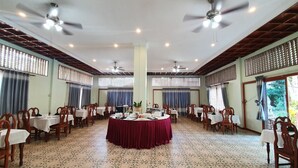 A spacious dining hall with round tables, wooden chairs, ceiling fans, and patterned floor tiles. - Sam Moon's Hotel Angkor (Siem Reap)