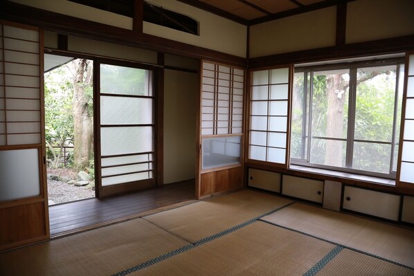A traditional Japanese room with tatami flooring, sliding doors, and large windows.