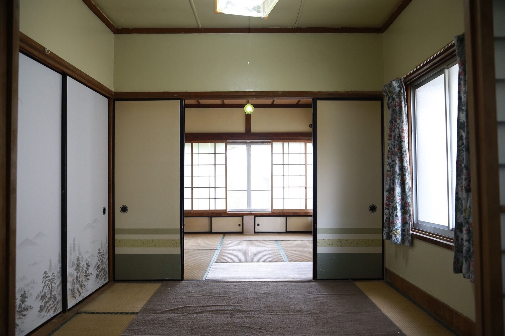 Una habitación japonesa tradicional con suelo de tatami, puertas correderas y un ventanal con vistas.