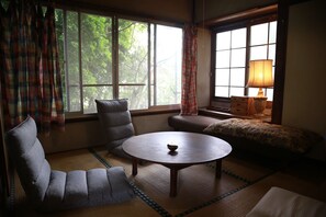 A room with a round table, two armchairs, a sofa, and a lamp.
