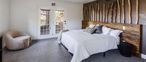 A bedroom with a bed, a chair, a ceiling fan, and a door with an exit sign.