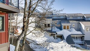 Un quartier résidentiel avec des maisons, un arbre et de la neige au sol.