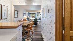 Un coin repas avec une table et des chaises en bois, un canapé et un tapis à motifs.