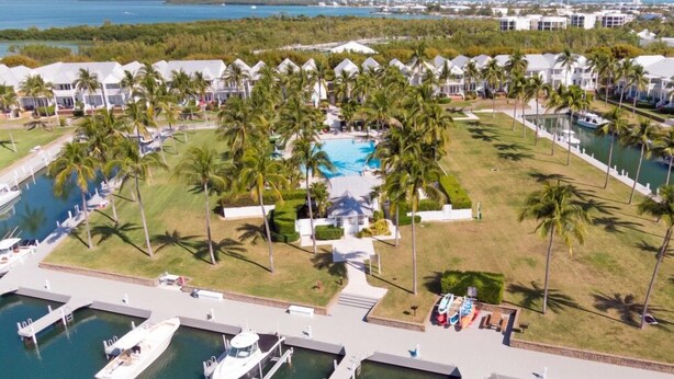 Ein Resort mit mehreren Villen, einem zentralen Pool und einem Yachthafen mit Booten.