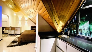 A modern kitchen with white cabinets and a black countertop, a dining area with a table and chairs, and a large window with a view of greenery. - Loft + private terrace with jacuzzi, fireplaces, cinema, panoramic view (Bogotá)