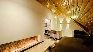 A modern bedroom with a sloped ceiling, a stone fireplace, a bed, and a small table with two chairs. - Loft + private terrace with jacuzzi, fireplaces, cinema, panoramic view (Bogotá)