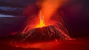 A volcanic eruption with lava flowing down the side of a mountain.