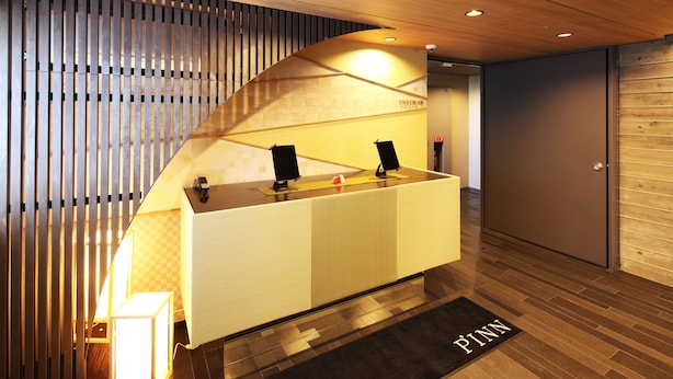 A reception desk with a check-in counter, a wooden slatted wall, and a black mat with "PENN" on it.