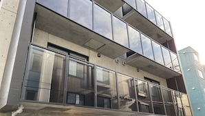A modern building with large windows, a balcony, and a visible entrance.