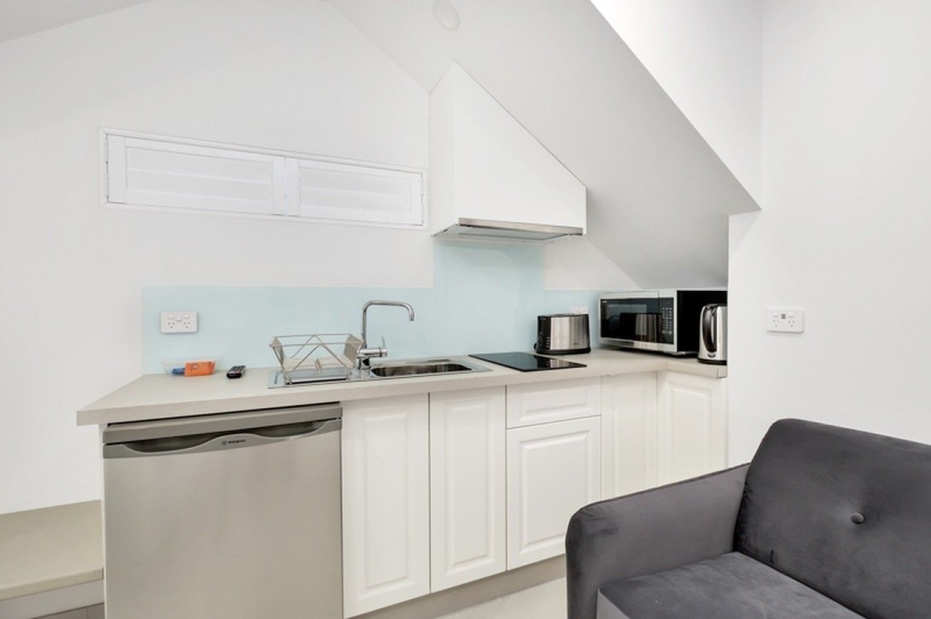 A compact kitchen with a dishwasher, a microwave, and a sink.