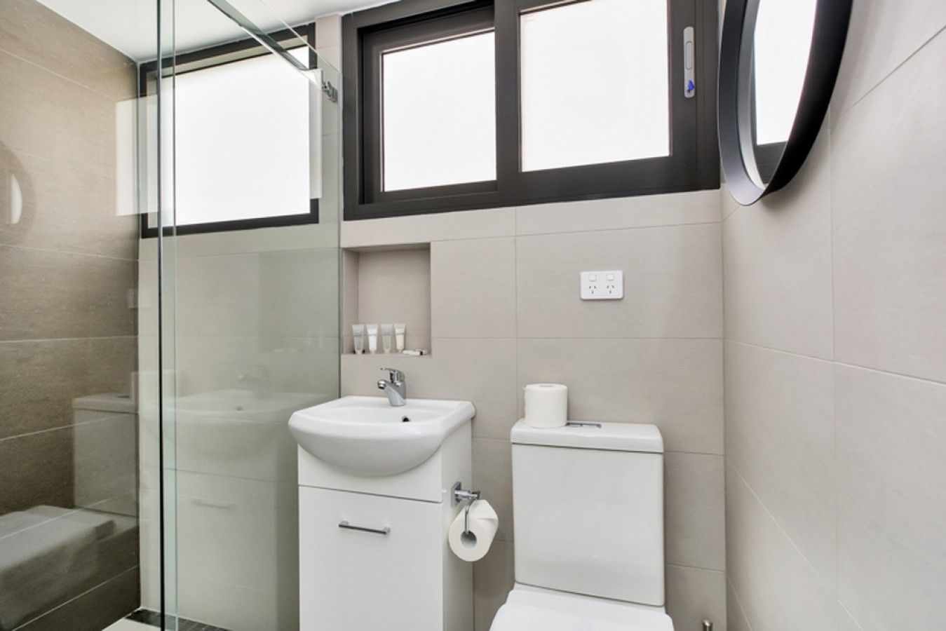 A modern bathroom with a glass shower enclosure, a white sink, and a toilet.