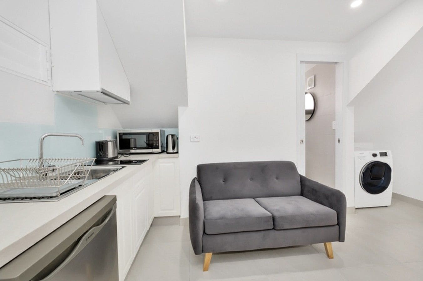 A modern kitchen with a dishwasher, microwave, and coffee maker.