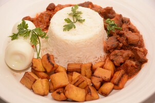 A plate of food with rice, meat, and fried plantains.