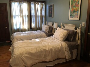 A bedroom with two beds, a wooden headboard, a nightstand, a lamp, and a painting on the wall.