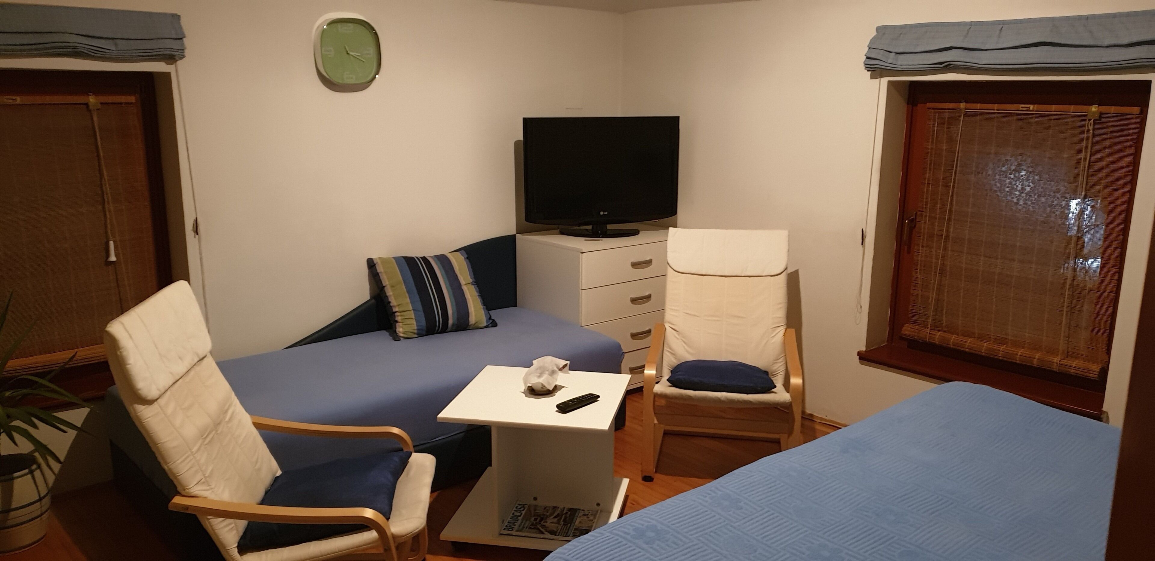 Una habitación pequeña y acogedora con una cama, una silla, un escritorio y un televisor.